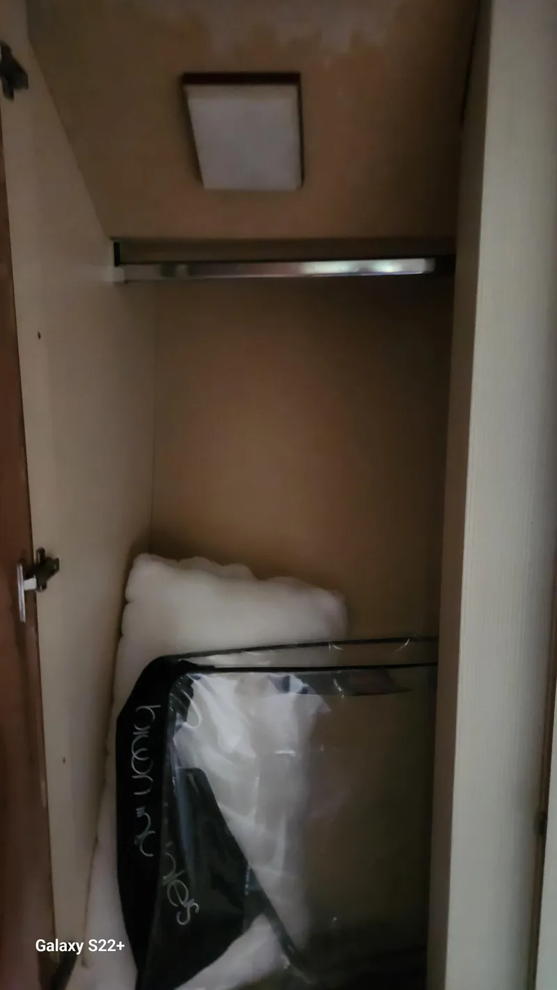 Slide: The Image of Storage compartment in 1998 Ferretti Yachts 55 Motor Yacht, with bedding and a suitcase. - 23