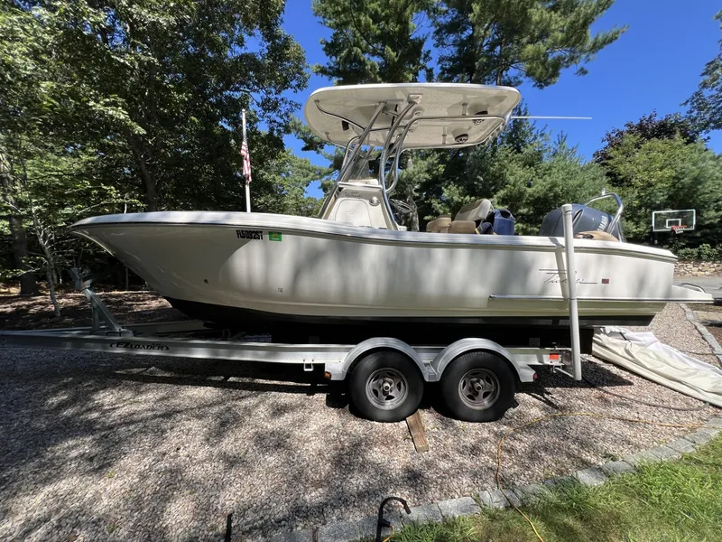 Slide: The Image of 2018 Pioneer 222 Islander boat on trailer, parked outdoors with trees in the background. - 12