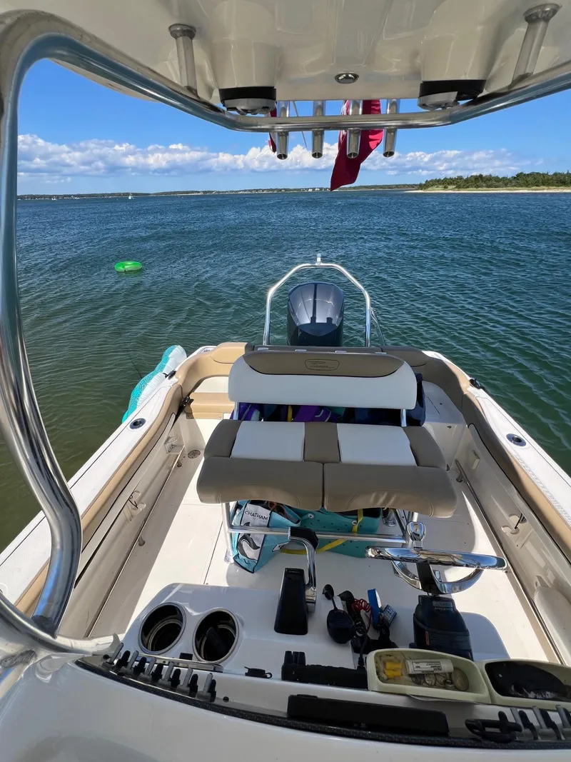 Slide: The Image of 2018 Pioneer 222 Islander boat on water, featuring spacious deck and seating, under clear blue sky. - 2