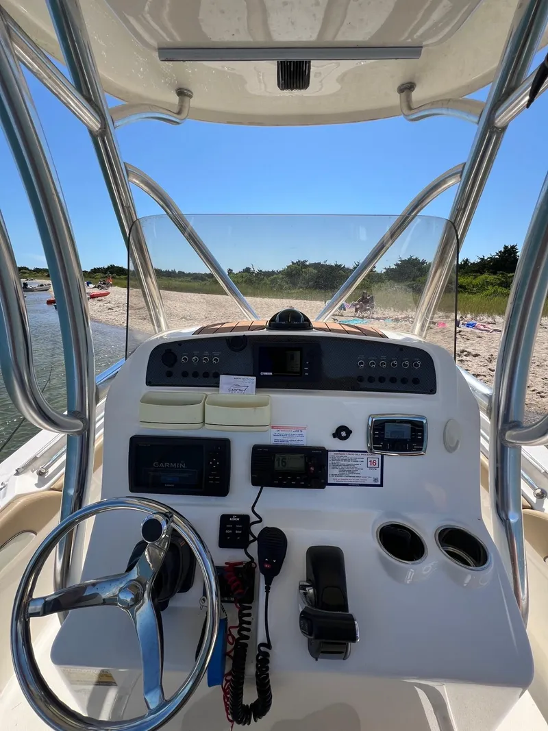 Slide: The Image of 2018 Pioneer 222 Islander boat dashboard with steering wheel and controls, near a sandy beach. - 9