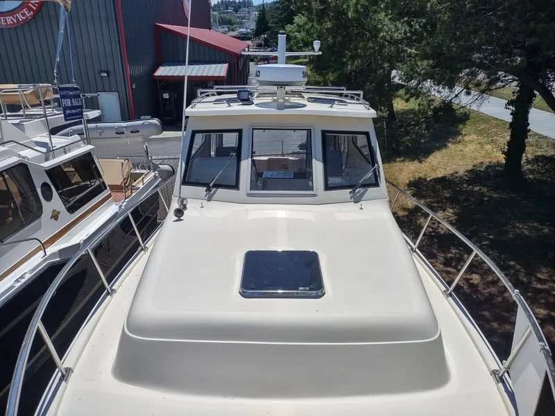 Slide: The Image of 2008 Mainship 30 Pilot II Sedan boat docked near trees and buildings. - 13
