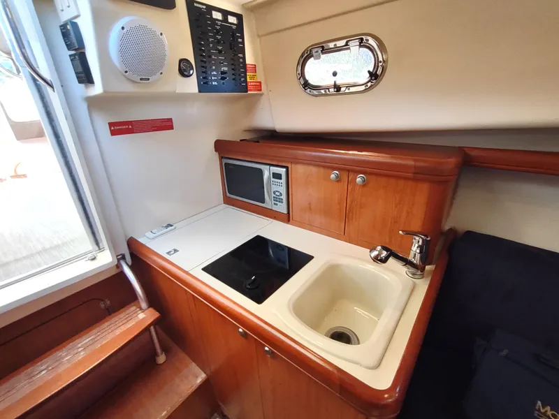 Slide: The Image of 2008 Mainship 30 Pilot II Sedan galley with sink, stove, and microwave. - 31