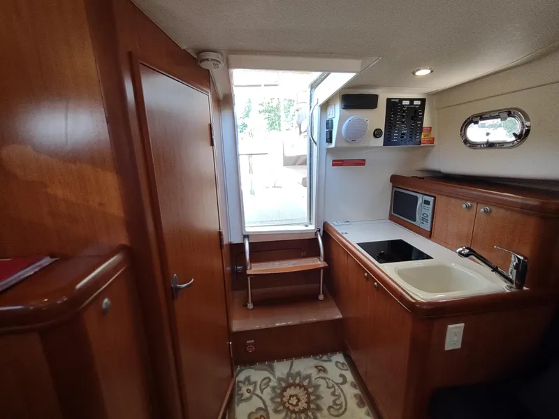 Slide: The Image of Interior of 2008 Mainship 30 Pilot II Sedan with kitchenette and wooden cabinetry. - 38