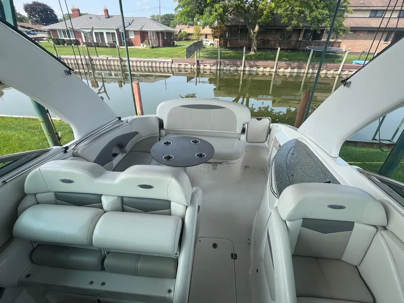 Slide: The Image of 2010 Chaparral 275 SSi boat interior with seating and table, docked by a waterfront. - 11