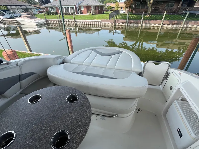 Slide: The Image of 2010 Chaparral 275 SSi boat interior with seating and table by a dock. - 13