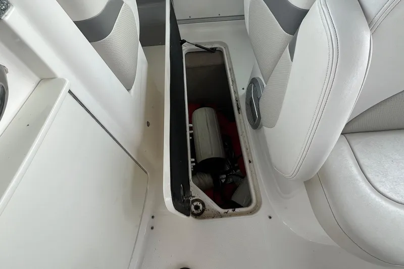 Slide: The Image of 2010 Chaparral 275 SSi boat storage compartment with open lid, revealing interior equipment. - 18