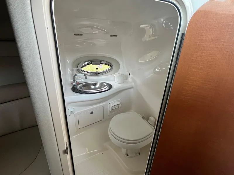 Slide: The Image of 2010 Chaparral 275 SSi boat bathroom with sink, toilet, and porthole window. - 26