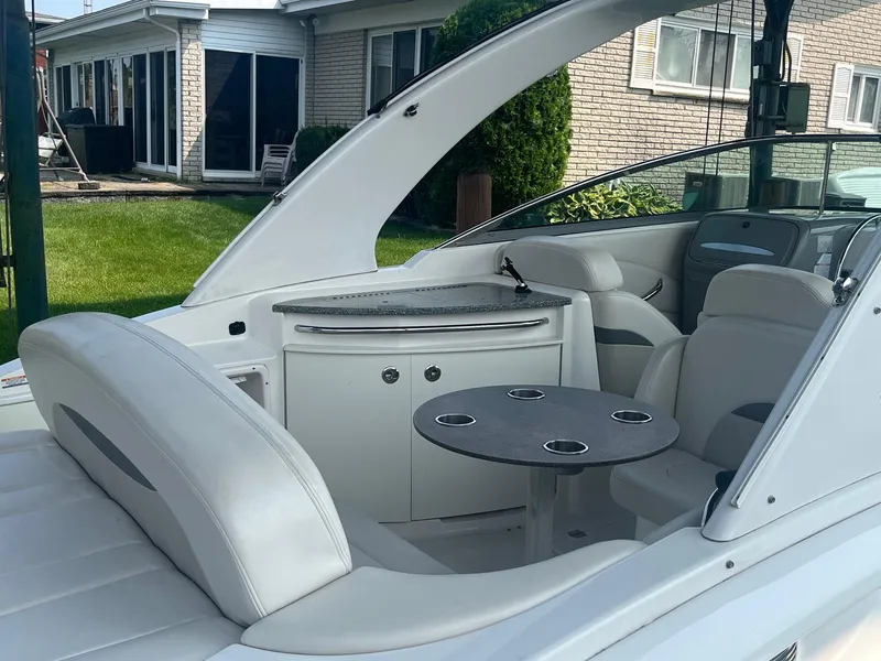 Slide: The Image of 2010 Chaparral 275 SSi boat interior with seating and table, near a house. - 9