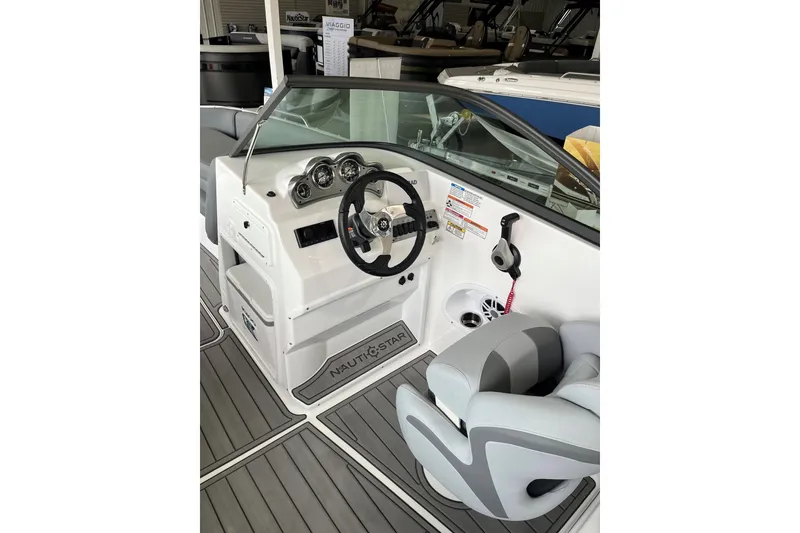 Slide: The Image of 2025 NauticStar 223 DC Deck boat interior with steering wheel and seating. - 15