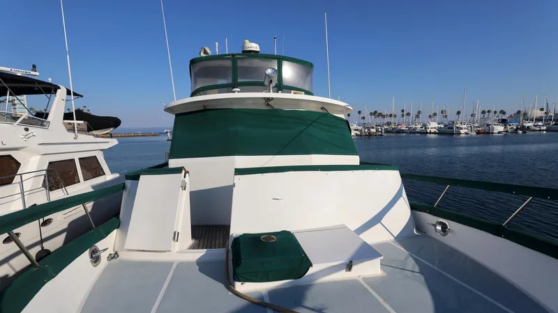 Slide: The Image of 1988 DeFever Pilot House yacht docked in a marina, featuring green and white exterior. - 21