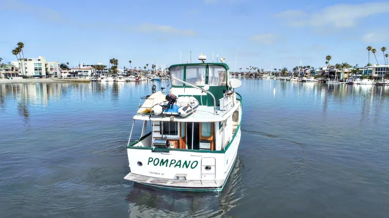 Slide: The Image of 1988 DeFever Pilot House boat named "Pompano" cruising in a calm marina. - 3