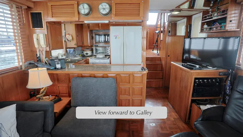 Slide: The Image of 1988 DeFever Pilot House interior with galley view, featuring wood paneling and modern amenities. - 4