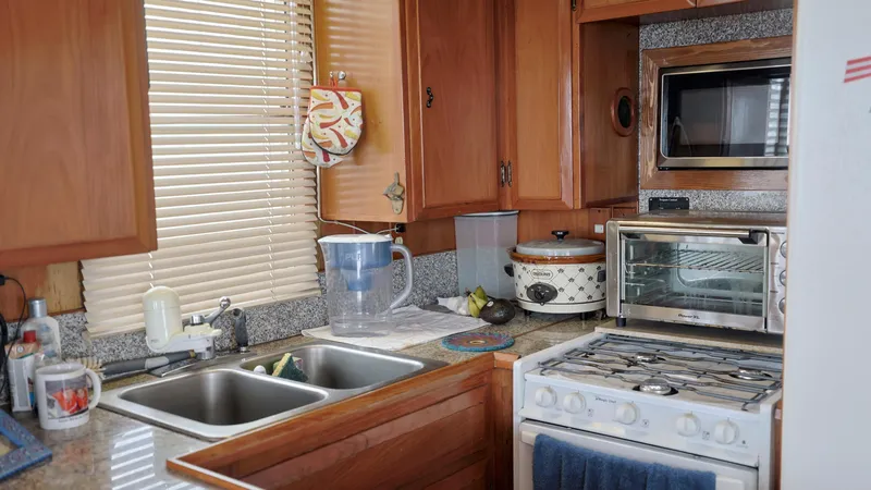 Slide: The Image of 1988 DeFever Pilot House kitchen with wooden cabinets, dual sink, stove, and appliances. - 9