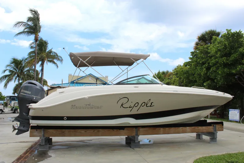 The Image of 2017 NauticStar 243DC Sport Deck boat on display with palm trees in the background. - 0
