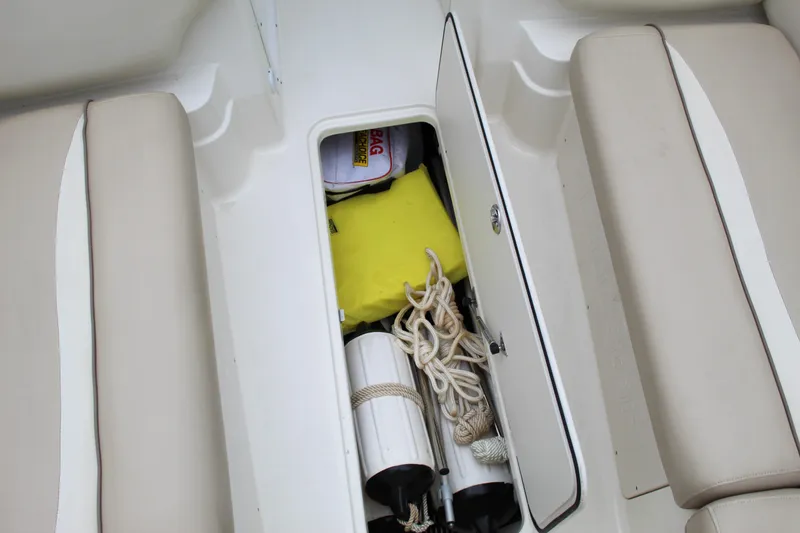 Slide: The Image of 2017 NauticStar 243DC Sport Deck storage compartment with ropes and safety gear. - 12