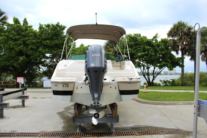 Slide: The Image of 2017 NauticStar 243DC Sport Deck boat on trailer, parked near lush greenery. - 16