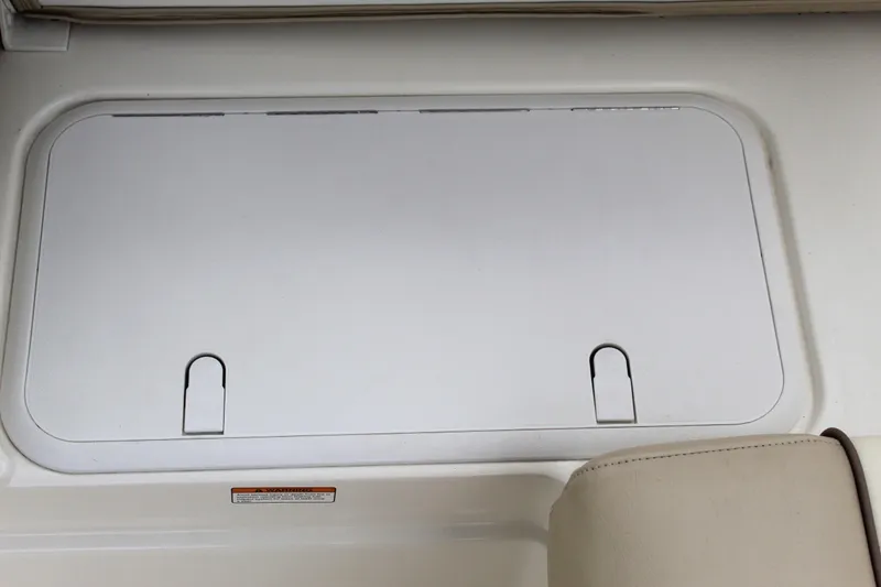 Slide: The Image of 2017 NauticStar 243DC Sport Deck storage compartment with white cover and beige seating. - 26