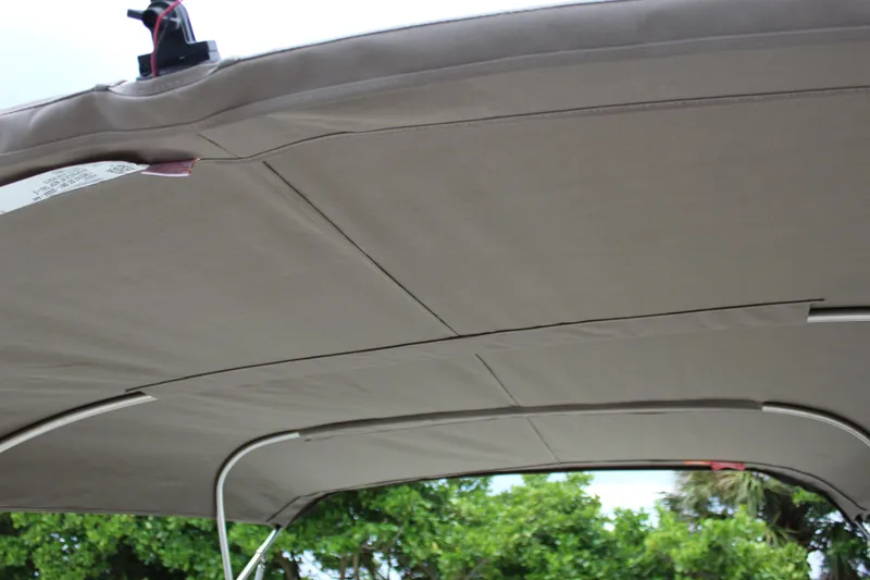 Slide: The Image of 2017 NauticStar 243DC Sport Deck boat canopy, beige fabric, outdoor setting. - 33