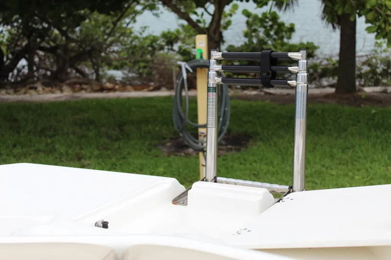 Slide: The Image of 2017 NauticStar 243DC Sport Deck boat ladder, surrounded by lush greenery. - 39