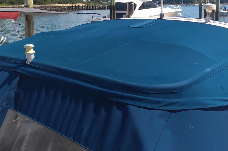 Slide: The Image of 2014 Sea Ray 300 SLX with blue canvas cover docked by the water. - 10