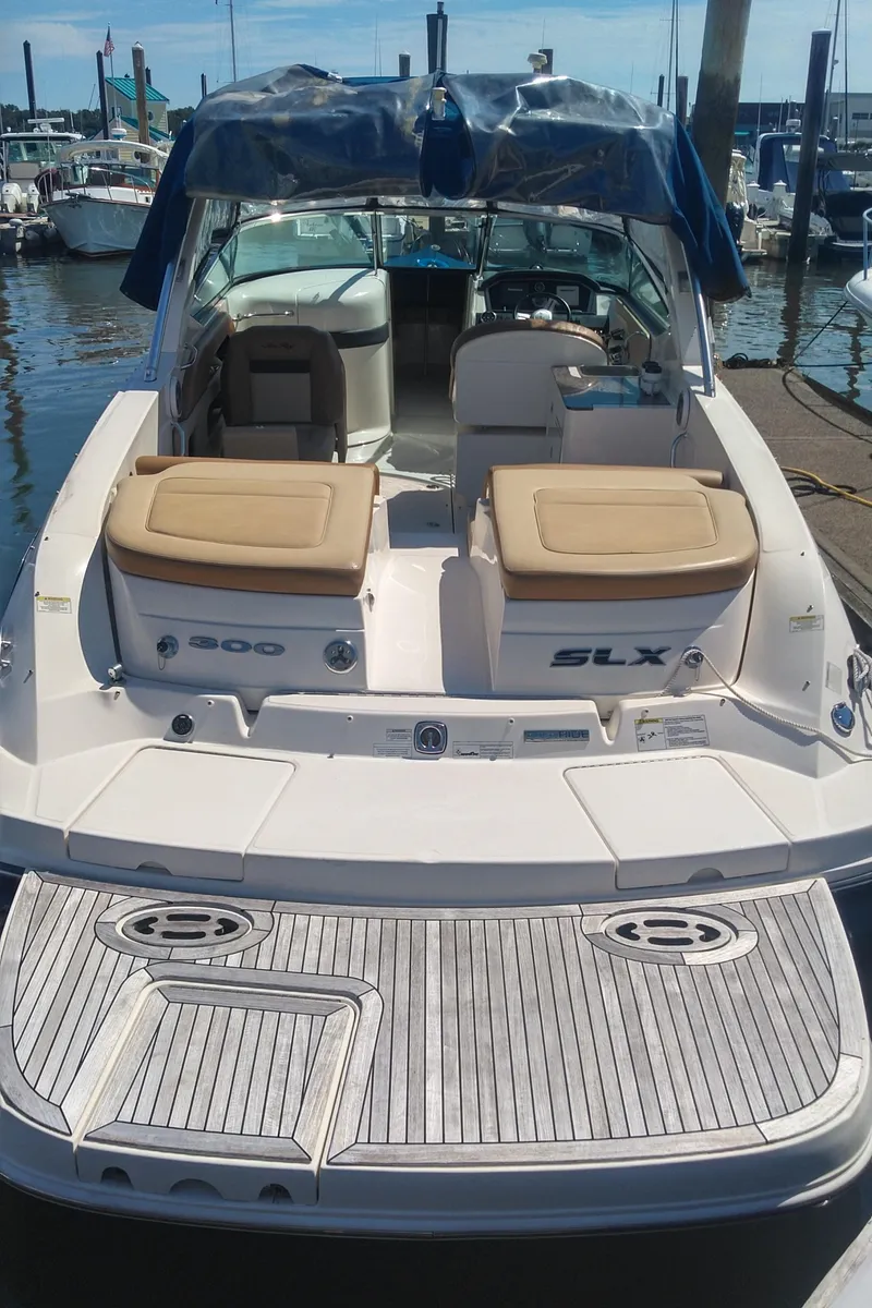 Slide: The Image of 2014 Sea Ray 300 SLX boat docked at marina, featuring spacious deck and seating. - 11