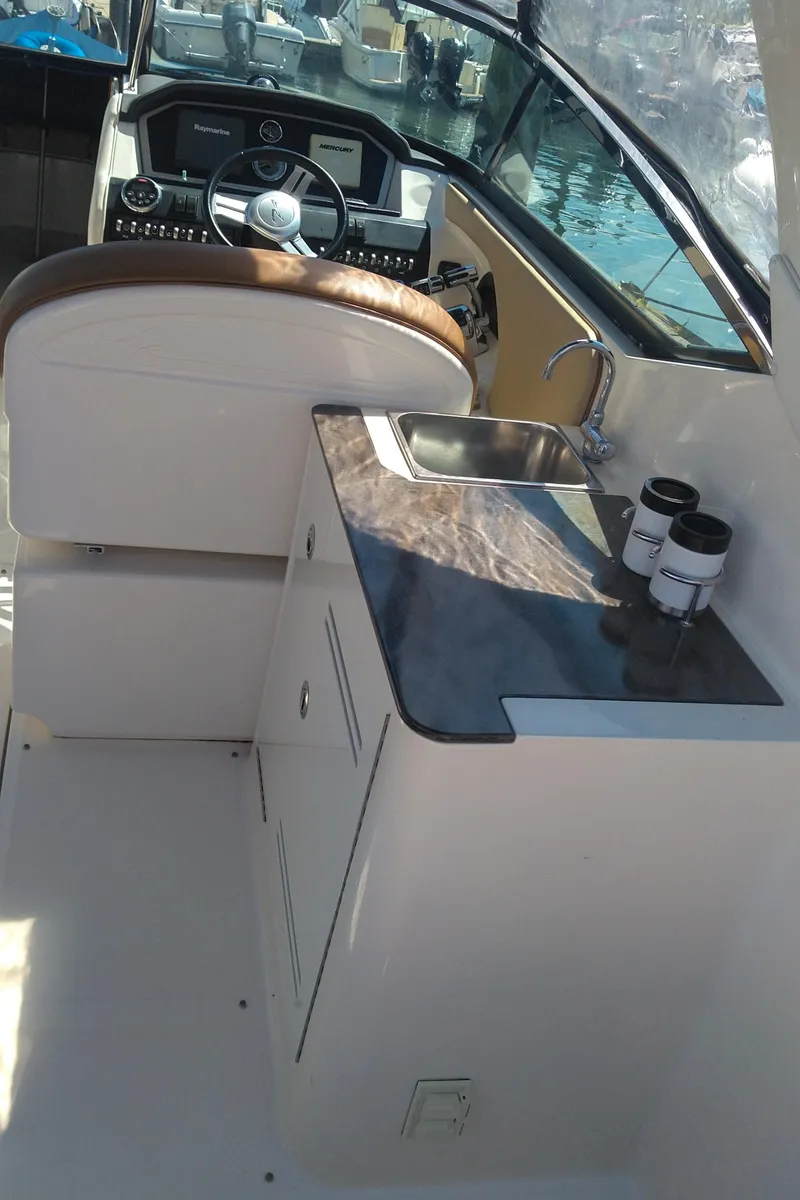 Slide: The Image of 2014 Sea Ray 300 SLX boat interior with helm and kitchenette area. - 12