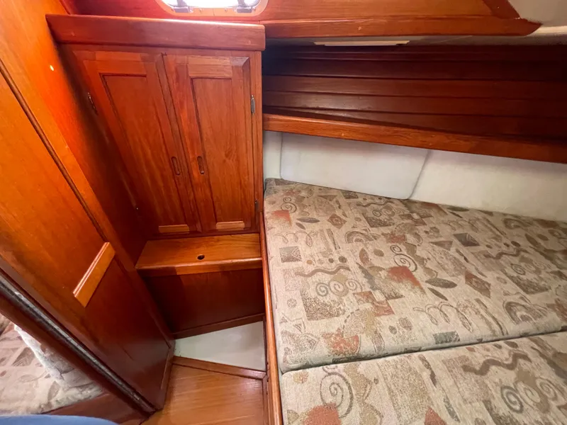 Slide: The Image of Cozy cabin interior of a 1990 Ericson 38-200 sailboat with wooden cabinetry and patterned cushions. - 14