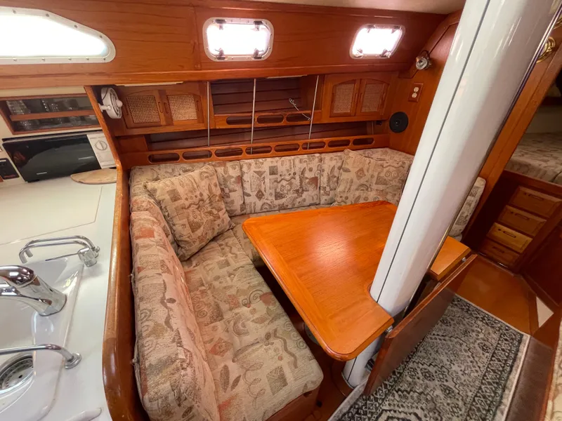 Slide: The Image of Cozy interior of 1990 Ericson 38-200 sailboat with cushioned seating and wooden table. - 19