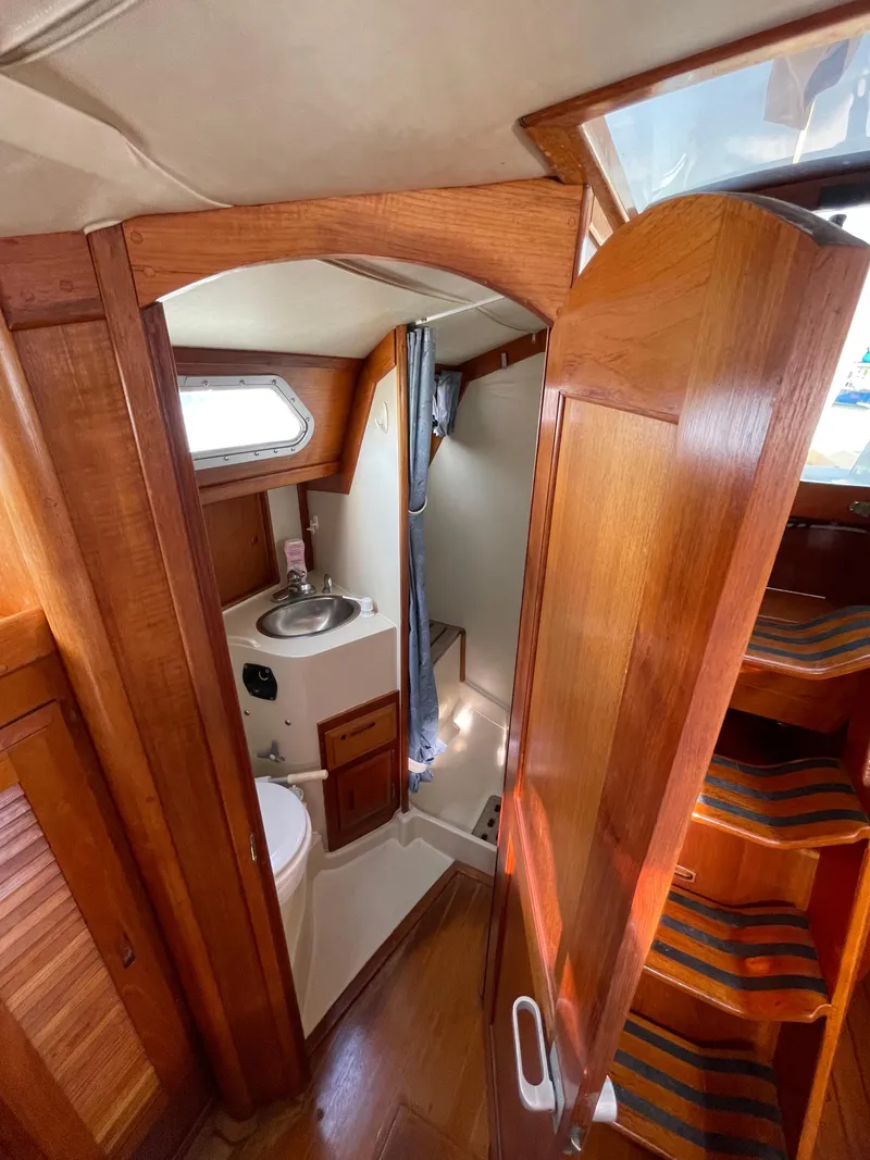 Slide: The Image of Interior of 1990 Ericson 38-200 sailboat, featuring compact wooden bathroom and steps. - 22