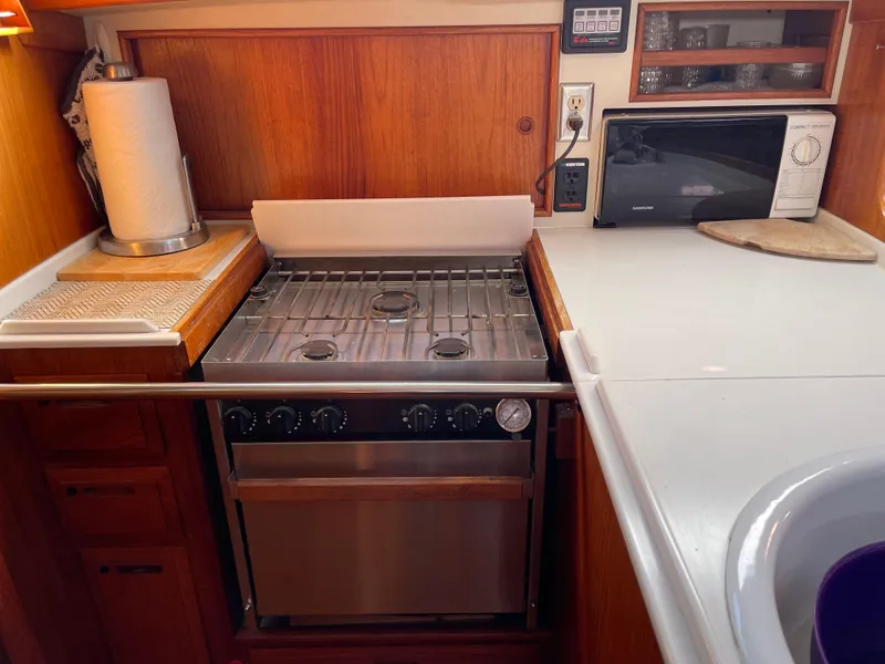 Slide: The Image of Compact kitchen in a 1990 Ericson 38-200 sailboat with stove, microwave, and wooden cabinetry. - 28