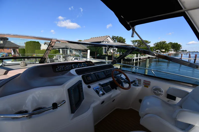 Slide: The Image of 1997 Sea Ray 400 Sundancer helm with waterfront view, featuring steering wheel and control panel. - 10