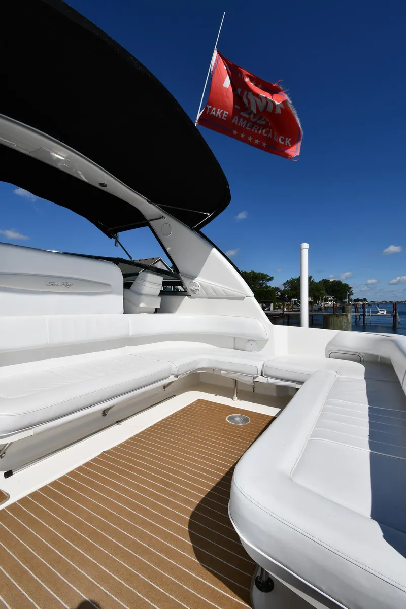 Slide: The Image of 1997 Sea Ray 400 Sundancer yacht with white seating and red flag, docked under clear blue sky. - 19