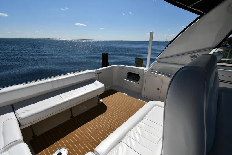Slide: The Image of 1997 Sea Ray 400 Sundancer yacht deck with ocean view, featuring white seating and wooden flooring. - 22