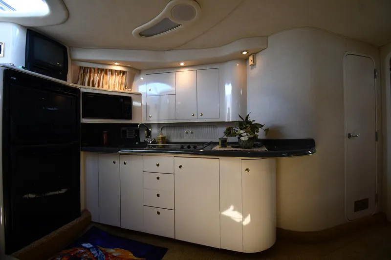Slide: The Image of Interior of 1997 Sea Ray 400 Sundancer yacht kitchen with white cabinets and appliances. - 41