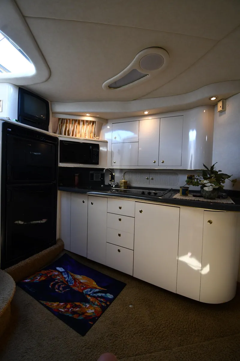 Slide: The Image of Interior of 1997 Sea Ray 400 Sundancer yacht kitchen with white cabinets and appliances. - 42