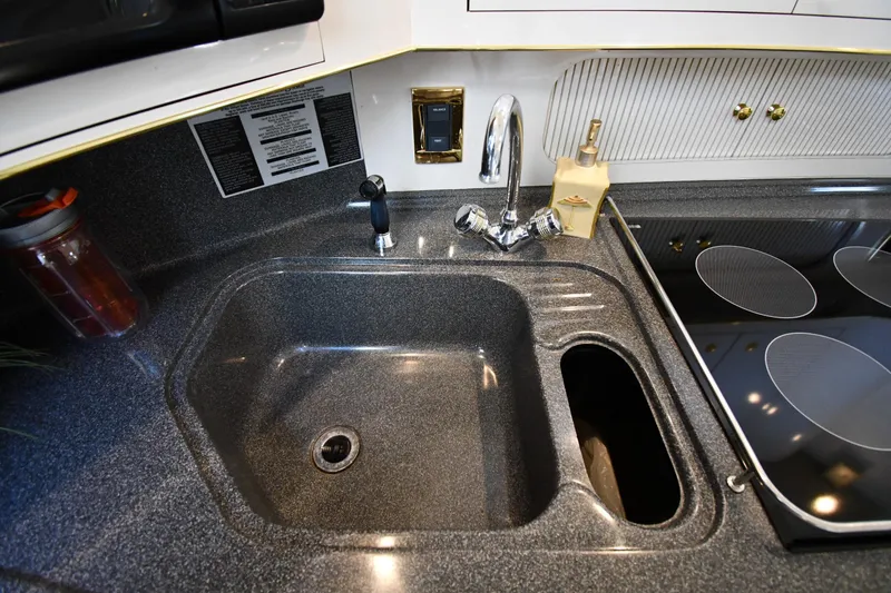 Slide: The Image of 1997 Sea Ray 400 Sundancer kitchen sink and stove area with modern fixtures. - 47