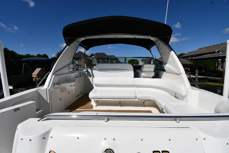 Slide: The Image of 1997 Sea Ray 400 Sundancer yacht with spacious white seating and black canopy under clear blue sky. - 7
