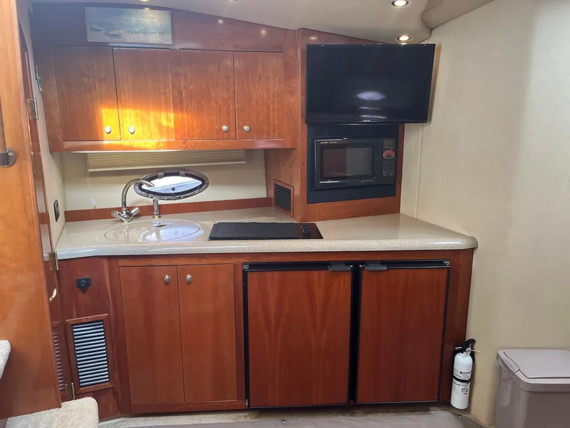 Slide: The Image of 2003 Cruisers Yachts 400 Express kitchen with wood cabinets, sink, microwave, and TV. - 11