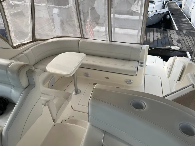 Slide: The Image of 2003 Cruisers Yachts 400 Express interior with seating and table, docked at marina. - 2