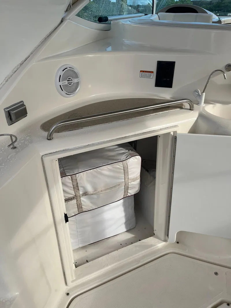 Slide: The Image of 2003 Cruisers Yachts 400 Express interior storage compartment with white cushions. - 5