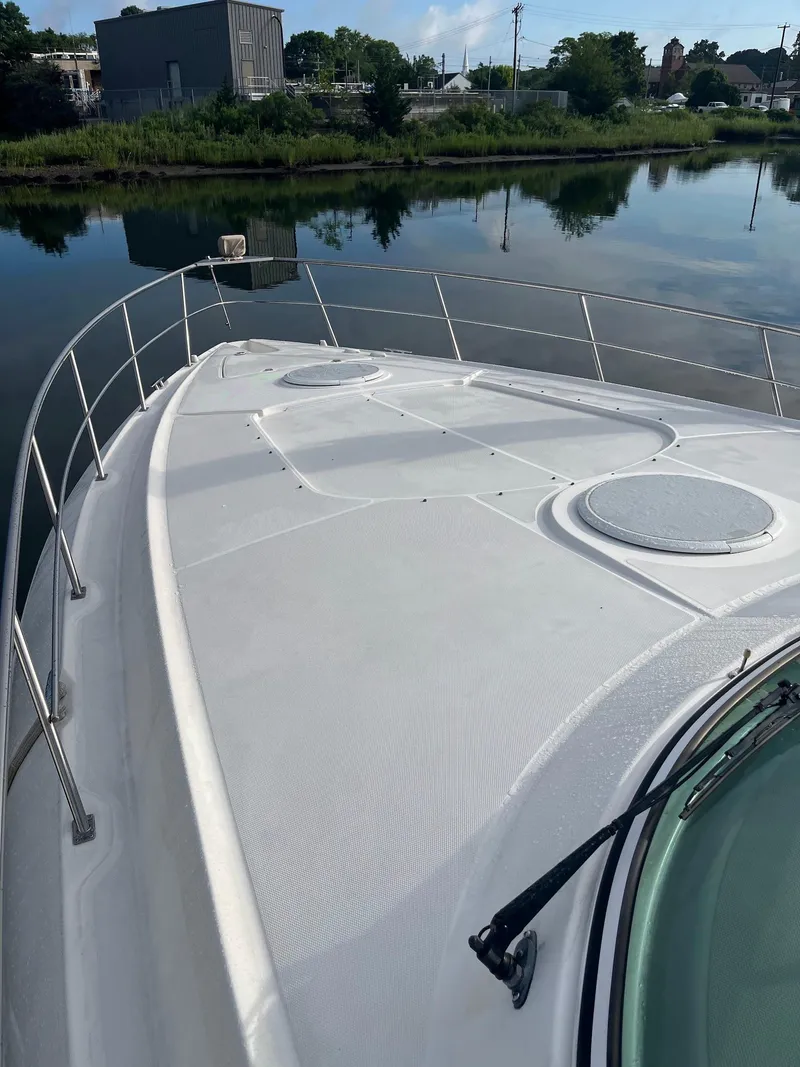 Slide: The Image of 2003 Cruisers Yachts 400 Express on calm water, showcasing sleek deck design. - 6