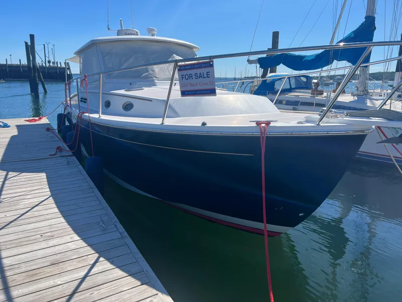 Slide: The Image of 2007 Back Cove 33 yacht docked in a serene marina setting. - 2
