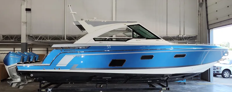 Slide: The Image of 2019 Formula 400 Super Sport Crossover boat in a garage, featuring a sleek blue and white design. - 0