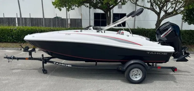 Slide: The Image of 2024 Tahoe T16 boat on trailer, black and white design, parked outdoors. - 0