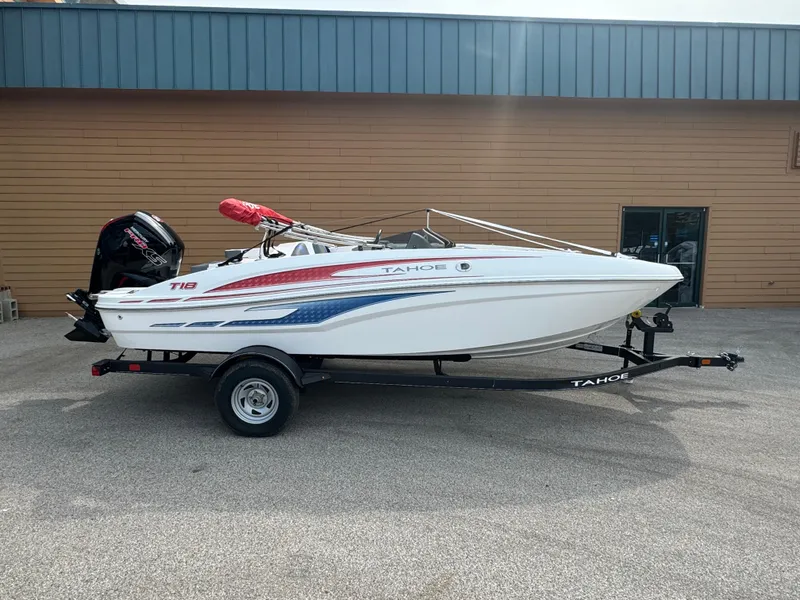 The Image of 2024 Tahoe T18 boat on trailer, white with red and blue accents, parked outdoors. - 0