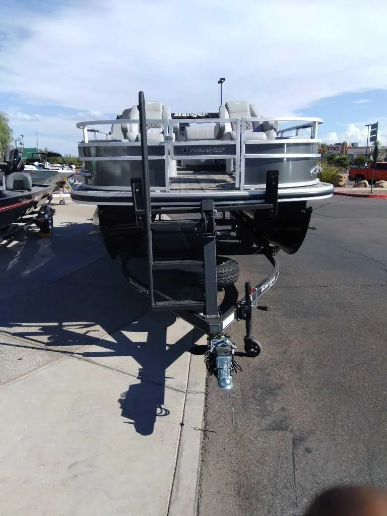 Slide: The Image of 2024 Ranger Reata 220F pontoon boat on trailer, parked on street. - 2