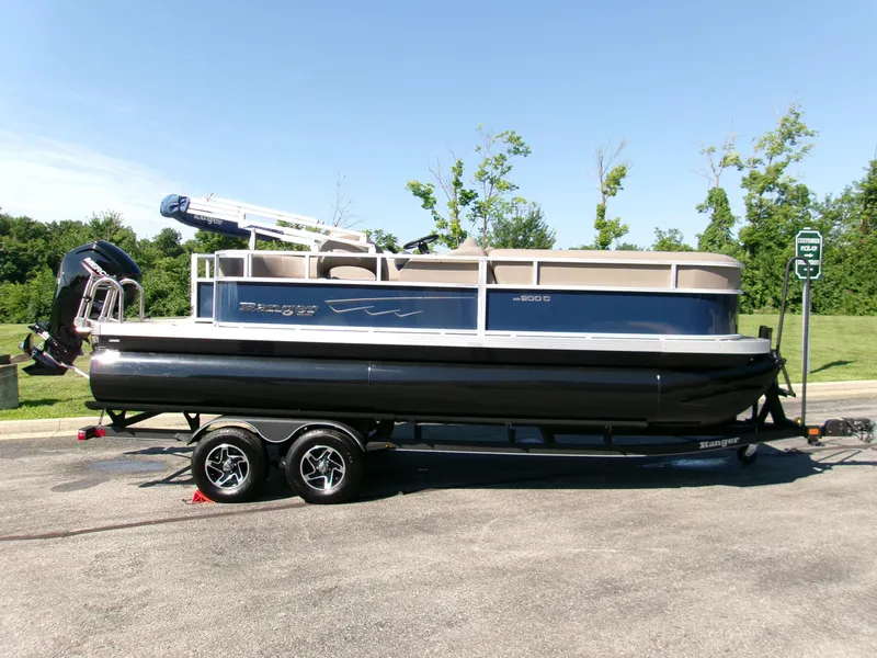 The Image of 2024 Ranger Reata 200C pontoon boat on trailer, parked outdoors on a sunny day. - 0