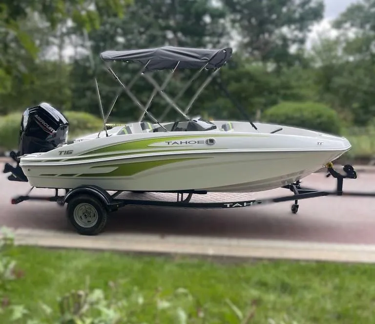Slide: The Image of 2024 Tahoe T16 boat on trailer with canopy, parked outdoors. - 0