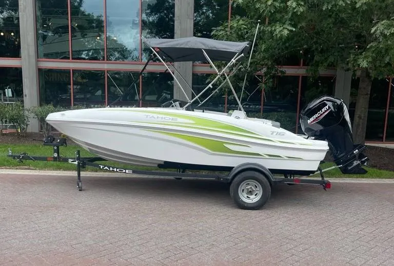 Slide: The Image of 2024 Tahoe T16 boat with trailer, parked outdoors, featuring sleek design and green accents. - 1