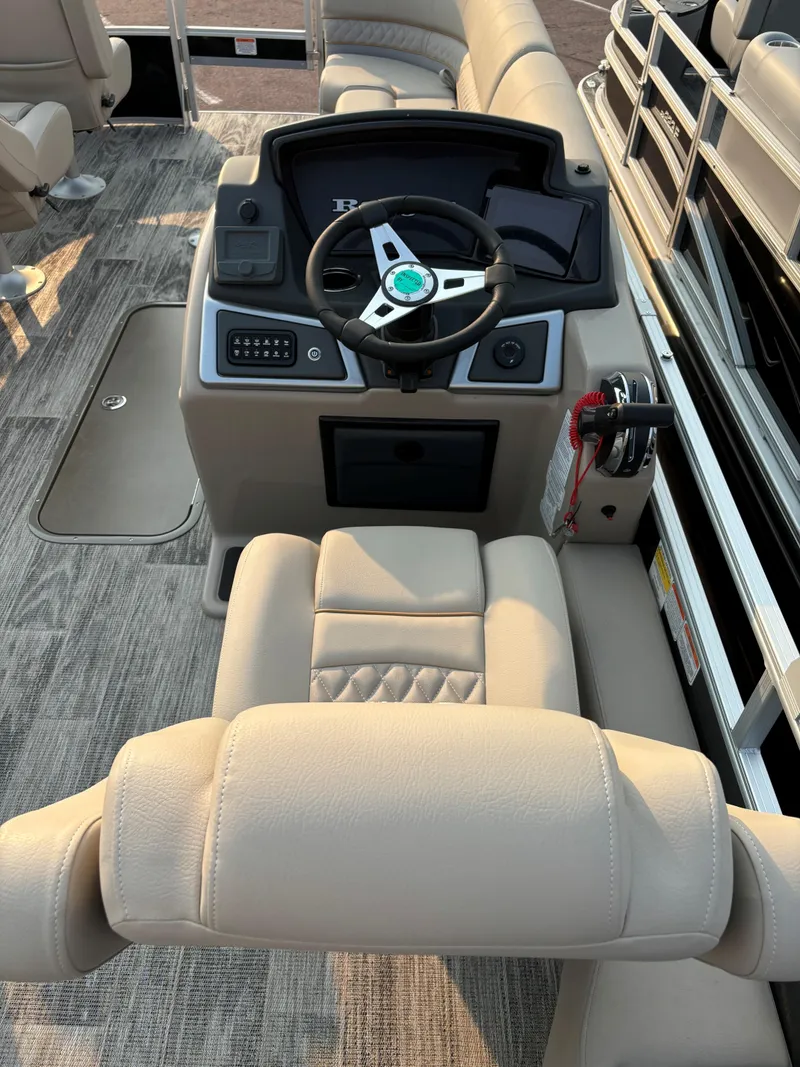 Slide: The Image of 2024 Ranger Reata 223FC boat interior with steering console and beige seating. - 5